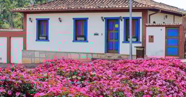 Casa colonial em Santa Bárbara com janelas azuis, telhado de barro e jardim florido em primeiro plan