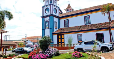 Igreja Matriz de Datas, em Minas Gerais, com fachada colorida e jardim florido