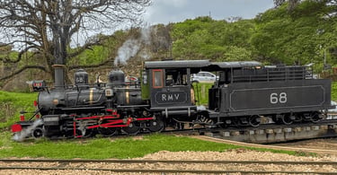 Maria-fumaça histórica sobre os trilhos em Tiradentes, com locomotiva a vapor e área verde ao redor