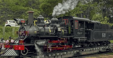 Locomotiva a vapor Maria Fumaça preta puxando vagões verdes na estação colonial de Tiradentes, MG