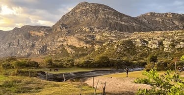 Montanhas de Lapinha da Serra ao entardecer, com campo aberto, lagoa rasa e paisagem rochosa