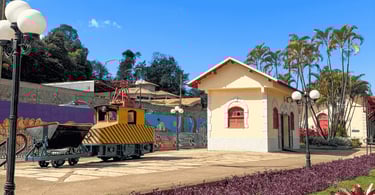 Museu Ferroviario em Itabirito com construção histórica, vagão de mineração e palmeiras ao fundo