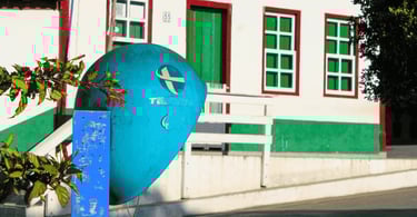 Casarão colorido em Ipoema MG com janelas verdes, detalhes vermelhos e antigo orelhão azul