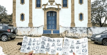Passaporte da Estrada Real com carimbos em frente à igreja histórica de Glaura, em Ouro Preto
