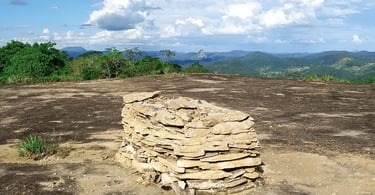 Estrutura de pedras sobre laje rochosa com montanhas e vegetação ao fundo em Concórdia do Mucuri