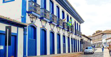 Prédio histórico de dois andares com sacadas de ferro e bandeira do Brasil no centro de Serro, Minas
