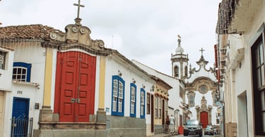 Rua charmosa ladeada por casarões coloniais com uma imponente igreja barroca em São João del Rei