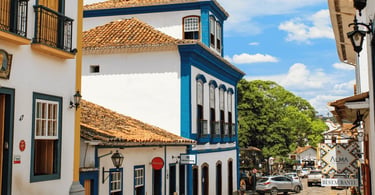Rua histórica de Tiradentes, com casario colonial, janelas azuis e movimento no centro