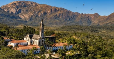 Santuário do Caraça em meio à natureza, com igreja histórica, palmeiras e a serra imponente ao fundo