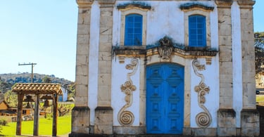 Capela histórica com porta azul e sino ao lado em Lobo Leite, distrito de Congonhas, Minas Gerais