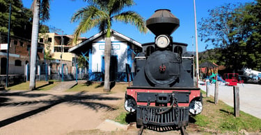 Trem histórico em Rio Acima MG em frente à antiga estação ferroviária e praça arborizada