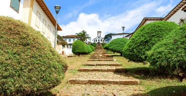 Escadaria da Igreja Santa Rita no Serro MG com caminho de pedras, jardins e igreja ao fundo
