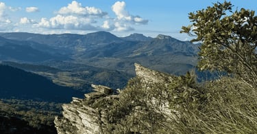 Vista das montanhas a partir do Morro Redondo, com céu azul e com nuvens, montanhas e vegetação
