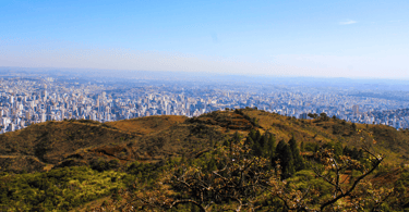Vista do Mirante da Serra do Curral, com a cidade de Belo Horizonte no fundo, montanhas e céu azul