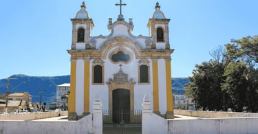 Fachada histórica de igreja com duas torres sineiras e detalhes em pedra. Ouro Branco