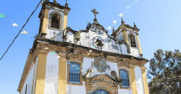 Fachada da Igreja Matriz de Itatiaia MG com torres, janelas azuis e bandeirinhas coloridas