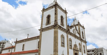 Igreja Matriz de Barbacena MG com torres, fachada histórica e céu nublado ao fundo