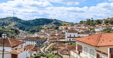 Vista do Serro, em MG, com casario colonial, telhados de barro e ruas entre morros ao fundo