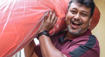 A man smiling and carrying a roll of fleece fabric on his shoulder