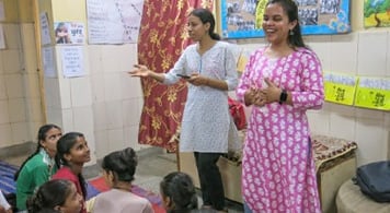 Ambassadors Pooga G and Priyanka standing at the front of a classroom