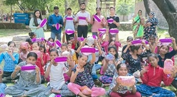 Girls and eight adults in a park holding up Hanaru's sanitary napkins.