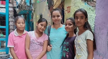 Priyanka standing in the centre of four girls in a slum area in Delhi.