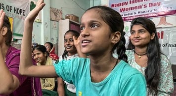 Girl in classroom with hand up.