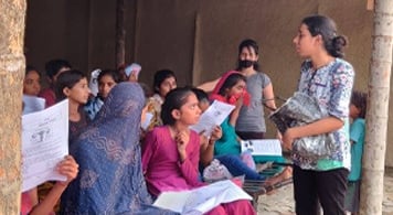 Group of girls listening to Pooja G giving menstrual education.
