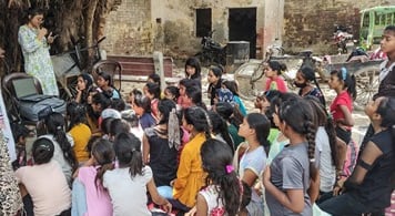 Group of girls listening to Pooja G giving menstrual education.