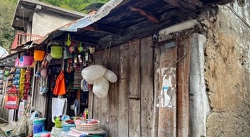 Shop made from wood and mud with  everyday items for sale outside.