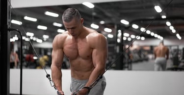 Muscular man performing a cable chest fly workout in a modern gym for strength training.