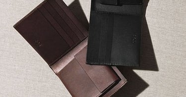 Carteras abiertas de cuero negro y marrón de dos pliegues con ranuras para tarjetas.