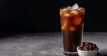 a glass of iced coffee with coffee beans