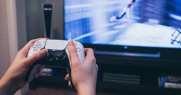 Jugador con mando de PS5 frente al TV, optimizando conexión y descargas en taller MBTECNIC.