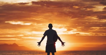 A person stands with open arms at sunset, expressing wonder, surrender, and spiritual searching.