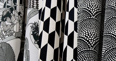 Black and white patterned upholstery fabric samples featuring geometric, floral, and dotted designs.