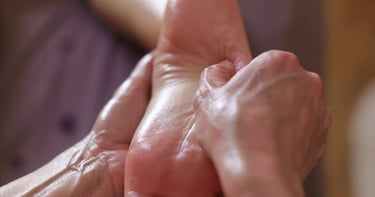 Massage du pied, geste lent et précis pour relâcher les tensions et inviter au lâcher-prise.