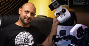 Una persona posando para la camara con su drone DJI en su mano izquierda