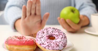 a person holding a doughnut and a cup of coffee green apple
