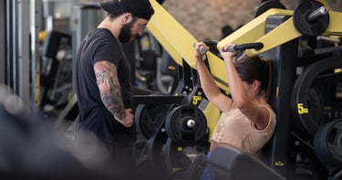 moi en train de coacher ma cliente emmie sur une shoulder press tecnogym