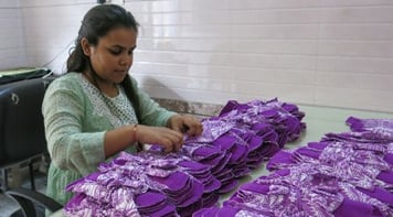 Priyanka seated tying up packs of reusable sanitar napkins. 