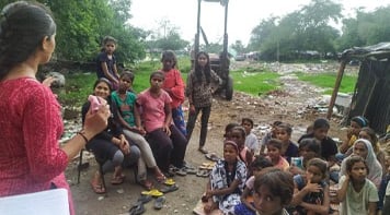 Pooja giving a talk to a group of girls on the edge of a slum.