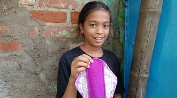 Girl holding up a reusable sanitary napkins.