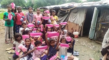 About twenty girls in a slum holding up Hanaru's sanitary napkins.