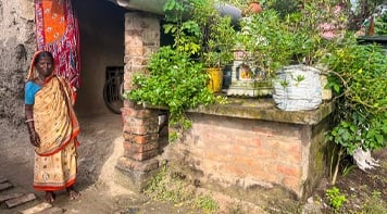 Woman in saree standing outside tiny home.