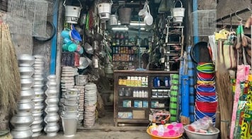 Tiny Indian shop crammed with saucepans and buckets and other household items for sale.