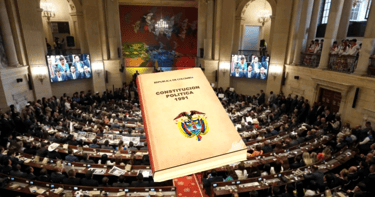 The 1991 Political Constitution of Colombia book overlaid on a crowded Colombian Congress session.