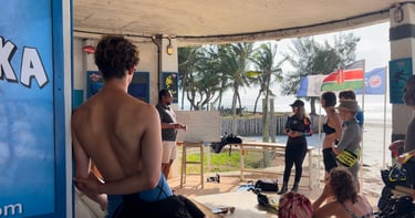 Scuba diving instructor giving a safety briefing to students on a tropical beach.