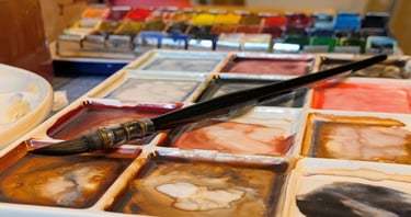 Waterverf palet met penseel en aquarel napjes, gemengde kleuren op een bord