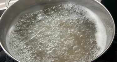 A large stainless steel pot filled with rapidly boiling water on a kitchen stove.
